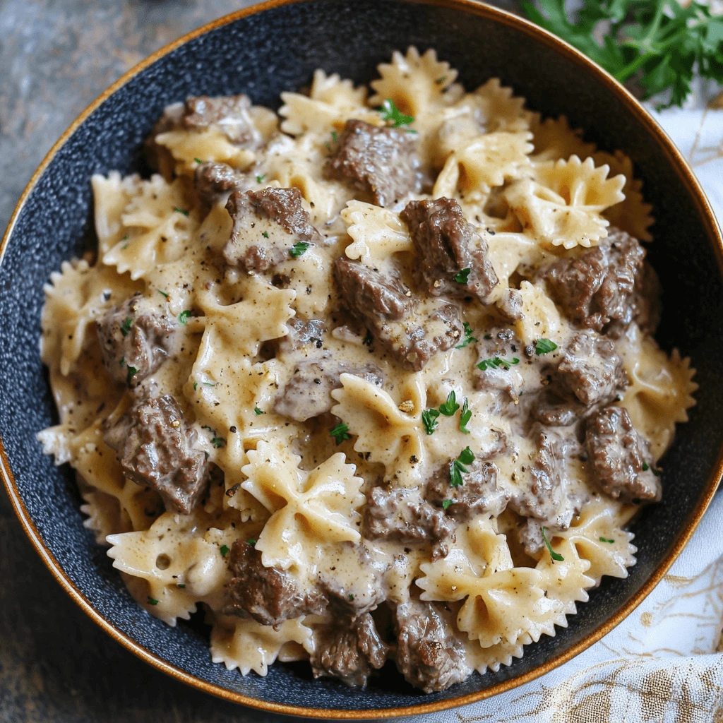 A delicious serving of Creamy Beef and Bowtie Pasta topped with freshly grated Parmesan cheese, accompanied by sautéed spinach and roasted cherry tomatoes.
