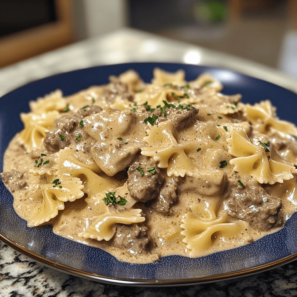 A plate of Creamy Beef and Bowtie Pasta garnished with Parmesan cheese, fresh spinach, and roasted cherry tomatoes.